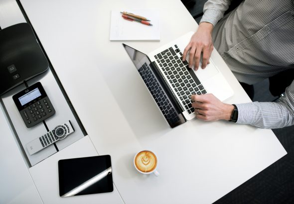 professionally dressed man using a laptop at an office desk