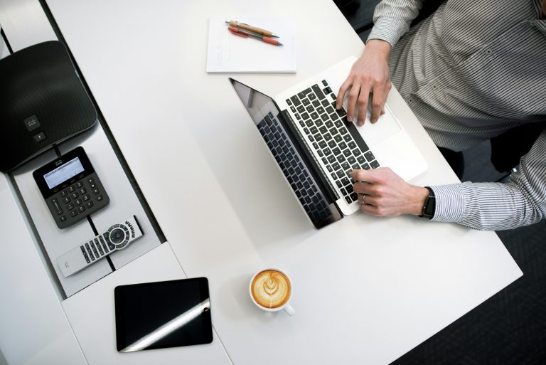 professionally dressed man using a laptop at an office desk